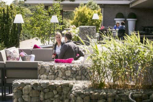 two people sitting on a stone bench in a garden at Van der Valk Hotel Assen in Assen