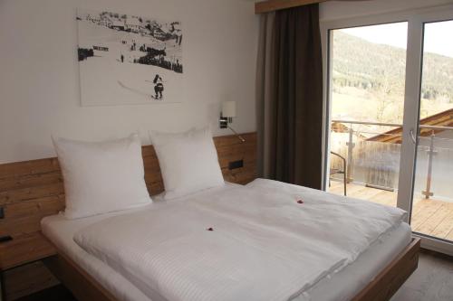 a bed in a room with a large window at Apart Alpin in Lermoos