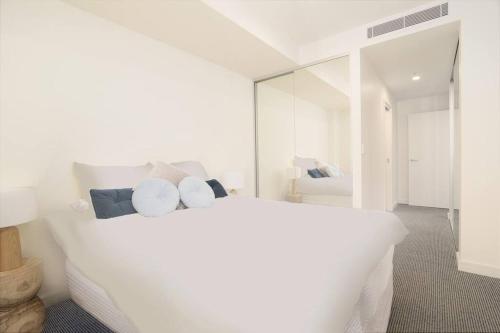 a white bedroom with a white bed and a mirror at Arena Newcastle Beach in Newcastle