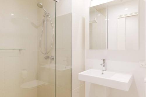 uma casa de banho branca com um lavatório e um chuveiro em Arena Newcastle Beach em Newcastle