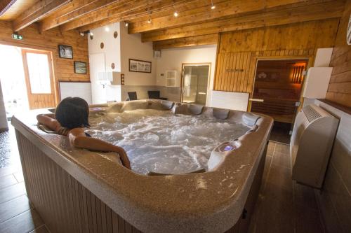 a woman sitting in a bath tub in a room at Logis Hôtel Centrotel et Spa Bulles d'Allier in Montmarault