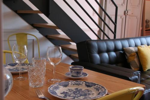 a wooden table with glasses and plates on it at Les Suites du Cours & Spa in Aix-en-Provence
