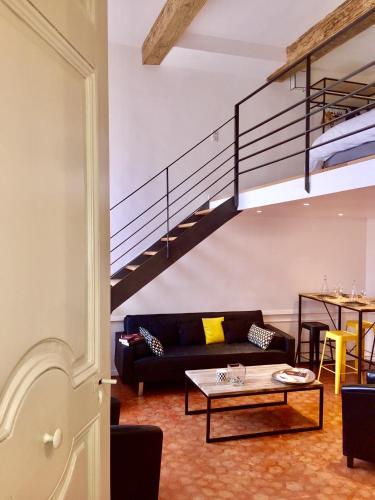 a living room with a couch and a staircase at Les Suites du Cours & Spa in Aix-en-Provence