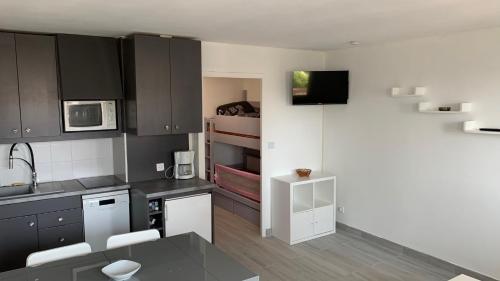 une cuisine avec des armoires noires et blanches et un évier dans l'établissement Appartement 4 personnes vue mer, coeur de ville, au Grau-du-Roi