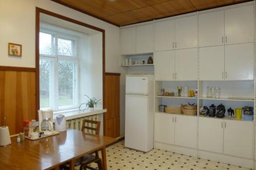 a kitchen with a table and a white refrigerator at Kihelkonna Pastorate Guesthouse in Kihelkonna