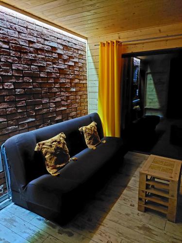 a black couch in a room with a brick wall at Domki przy Młynie " Koło Młyńskie " in Krościenko