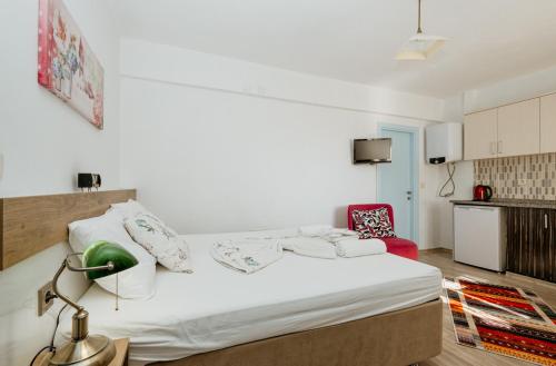 a bedroom with a white bed and a red chair at Azra Apart & Otel in Gokceada Town