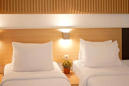 two beds in a hotel room with white pillows at Malaka Hotel Bandung in Bandung
