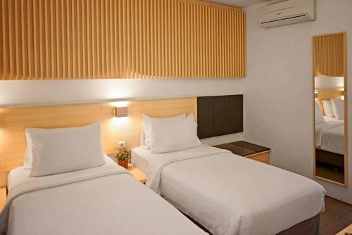 a hotel room with two beds and a mirror at Malaka Hotel Bandung in Bandung