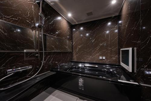 baño con paredes de mármol negro y ducha en BAMBOO GARDEN 相模原, en Sagamihara