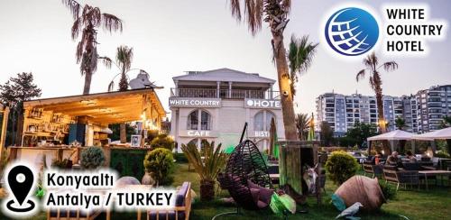 a white house with palm trees and a building at White Country Boutique Hotel in Antalya