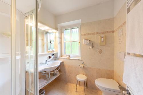 Monza Dolomites Hotel في موينا: حمام مع حوض ومرحاض ونافذة