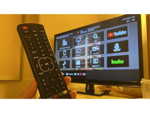 a person holding a remote control in front of a television at Az Inn Fukui - Vacation STAY 65935v in Fukui