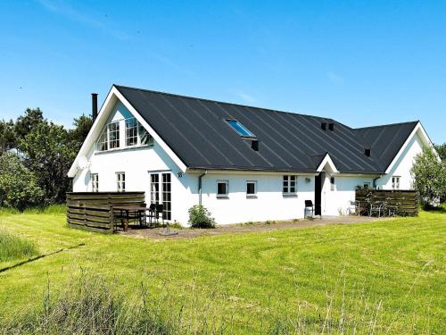 een wit huis met een zwart dak op een veld bij 10 person holiday home in Thisted in Thisted