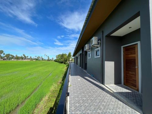 a building with a green field next to it at ลานนา รีสอร์ท in Ban Thap Khang
