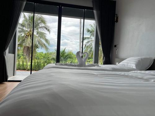 uma cama branca com uma almofada de coração em frente a uma janela em ลานนา รีสอร์ท 