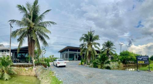 a car parked in front of a house with palm trees at ลานนา รีสอร์ท in Ban Thap Khang