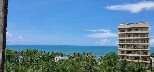 um edifício alto com o oceano ao fundo em BB Hotel&Resort em Phu Quoc