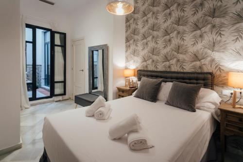 Un dormitorio con una cama blanca con toallas. en Precioso apartamento con patio en La Alameda, en Sevilla