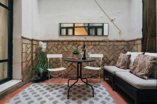 patio con mesa, sillas y ventana en Precioso apartamento con patio en La Alameda, en Sevilla