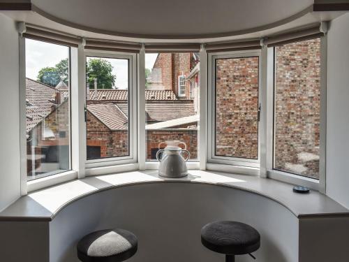 a room with windows with two stools and a tea kettle at The Turret in Easingwold