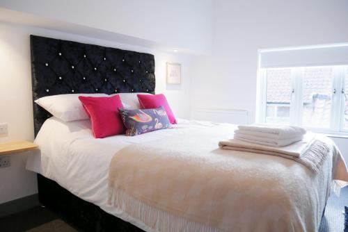a bedroom with a large bed with pink and white pillows at 2 bed luxury duplex apartment in heart of Holt in Holt
