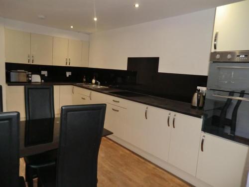 uma cozinha com armários brancos e bancadas pretas em Luton, LU3 Double Ensuite room em Luton