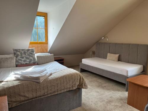 a attic bedroom with two beds and a window at Penzion Bawaria in Horní Lomná