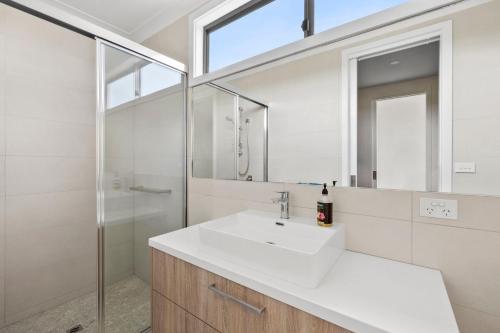 a white bathroom with a sink and a shower at Aireys Sunset Beach House in Aireys Inlet