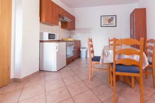 eine Küche mit einem Tisch, Stühlen und einer Mikrowelle in der Unterkunft Apartments Sunset -near Queen Beach in Privlaka