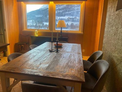 a wooden table in a room with chairs and a window at Koselig og sentral hytte midt i Hemsedal in Kyrkjebøen