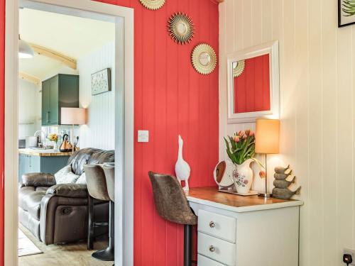a living room with red walls and a dining room at Ponsford Ponds - Goosedown Lodge in Cullompton