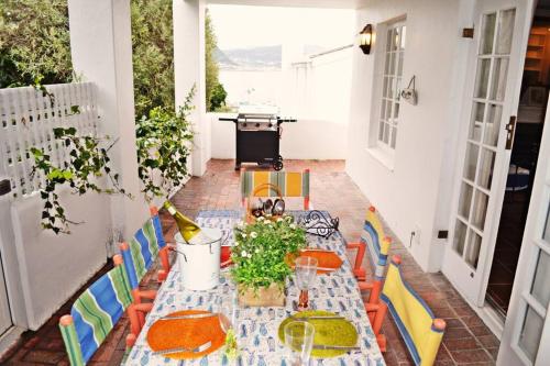 een tafel en stoelen op een patio met een tafel en een grill bij Bougainvillea House - The Heart of Simonstown in Simonʼs Town