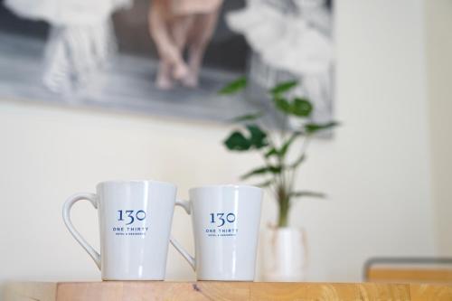 two white coffee mugs sitting on a table at 130 Hotel & Residence Bangkok in Bangkok