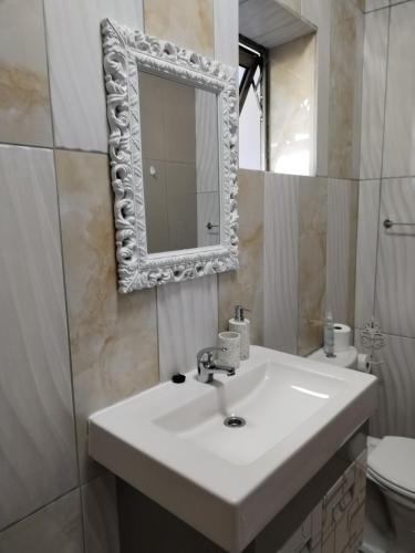 a bathroom with a sink and a mirror and a toilet at Nais cottage in Cape Town