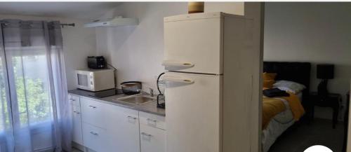 - une cuisine avec un réfrigérateur blanc et un lit dans l'établissement R1/logement proche de Paris - VILLIERS LE BEL (95), à Villiers-le-Bel