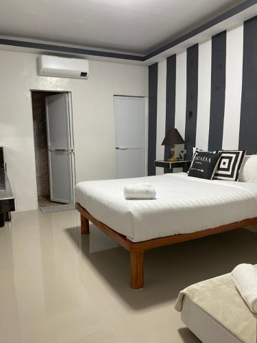 1 dormitorio con cama y pared a rayas en RedDoorz @ Piamonte Apartelle Santo Tomas Batangas, en Santo Tomás