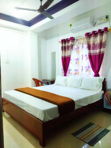 a bedroom with a large bed with pink curtains at Continental Homestay in Port Blair