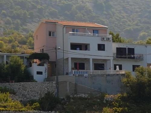 duży biały dom na szczycie wzgórza w obiekcie Apartmani Jereb w mieście Drašnice