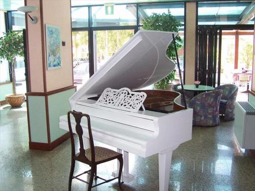 a white piano sitting in a room with a chair at Hotel Mirage in Lido di Classe