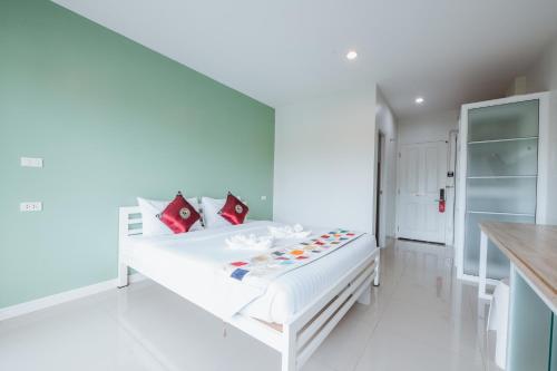 a white bed in a white room with red pillows at UR The Private Huahin in Hua Hin