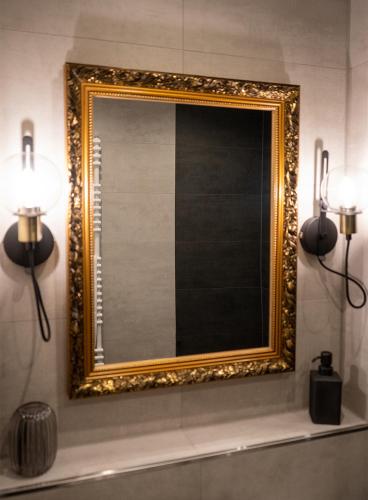 a gold framed mirror on a wall in a bathroom at Hotel Haus Hohenstein in Witten