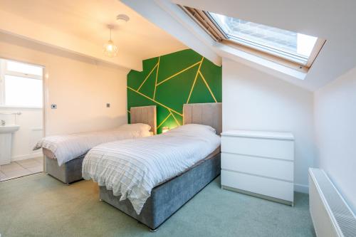 two beds in a bedroom with a green wall at Stylish 3 Bed - Entire House- Near City Ctr & SUFC in Sheffield