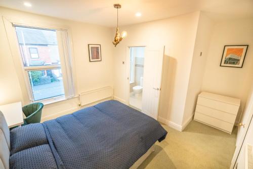 a bedroom with a blue bed and a window at Stylish 3 Bed - Entire House- Near City Ctr & SUFC in Sheffield