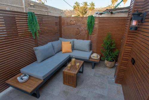 a patio with a blue couch and two tables at kadarim Boutique Suites-beachfront Zimmer in Haifa