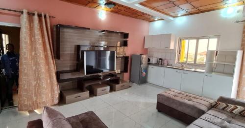 a living room with a large tv and a kitchen at Résidence Diakhaby in Conakry