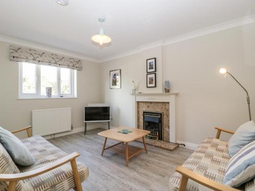 a living room with a fireplace and a table at The Beach House in Bridport