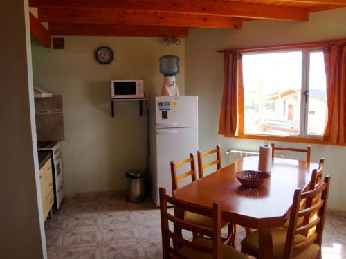 a kitchen with a table and a white refrigerator at Apart Don Felipe in El Calafate