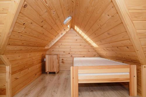 a wooden cabin with a bed in a attic at Spisz& Śpisz in Frydman