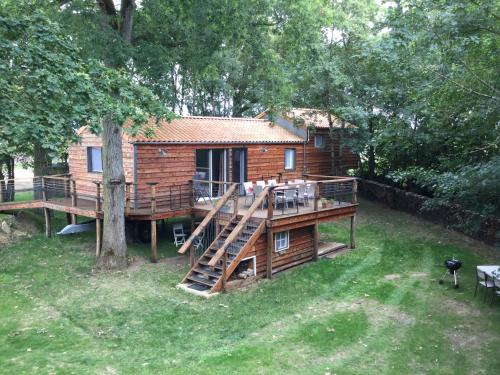 eine Blockhütte mit einer Veranda und einer Terrasse in der Unterkunft COLIBRI LOC - insolite - 3 étoiles - PARC - ETANG - FAMILLES - SOIREE OK in Brigné